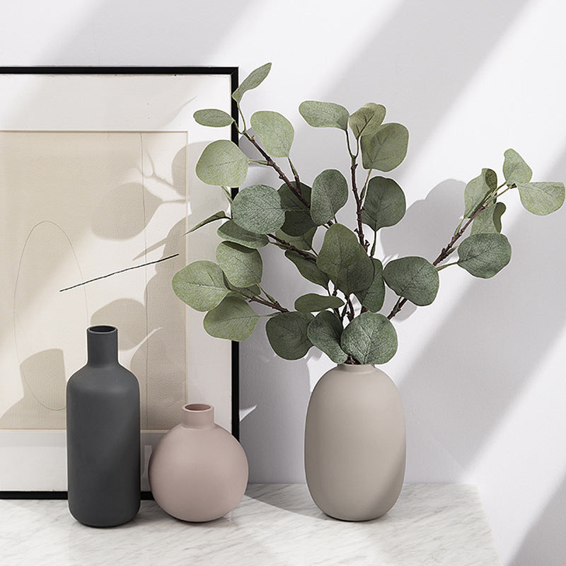 Nordic ceramic vase trio holding eucalyptus stems on a marble shelf