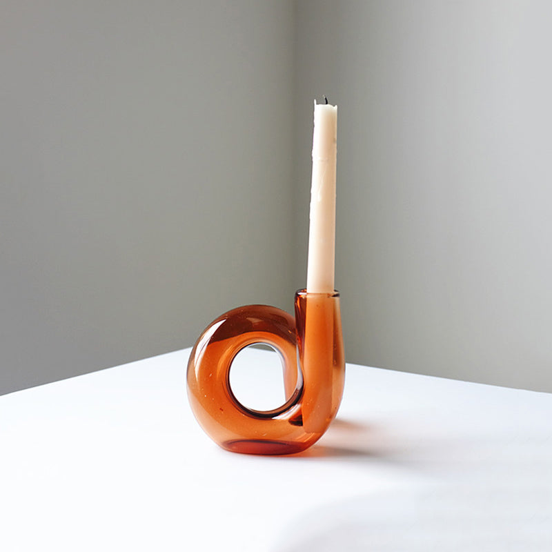 Sculptural amber glass candle holder with a cream taper candle on a minimalist plinth