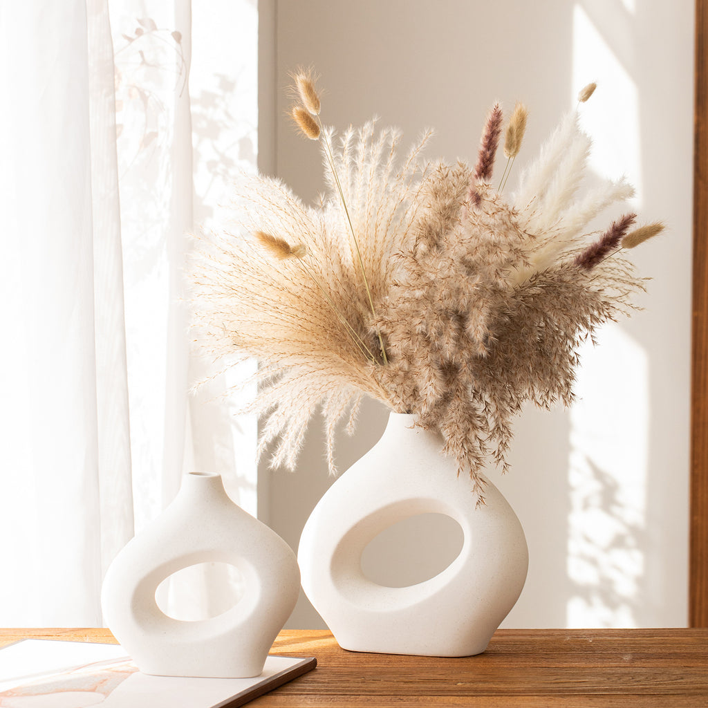 White sculptural hollow vases with dried pampas in a sunlit room