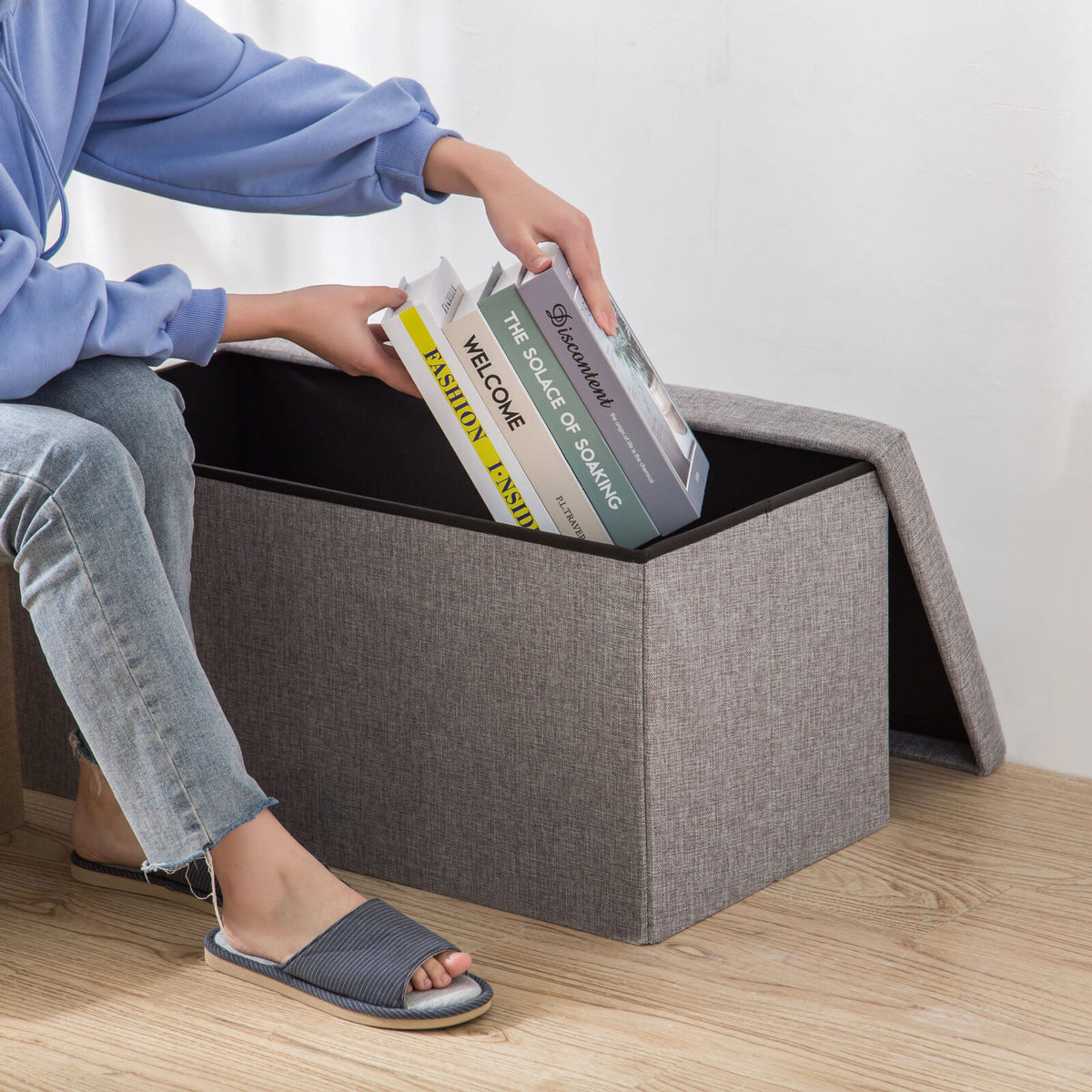 Grey storage ottoman footstool open with books inside