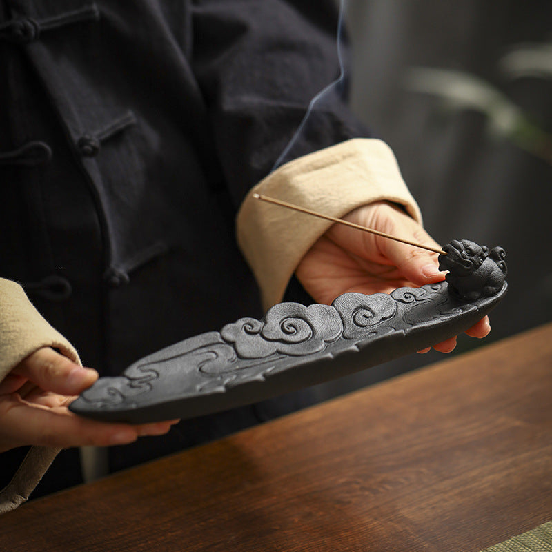 Close-up of matte black ceramic incense stick holder with carved cloud relief