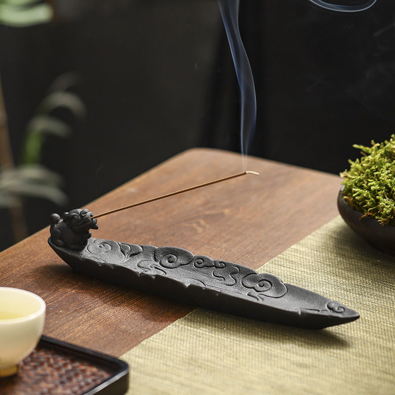 Matte black ceramic incense stick holder styled on a wooden tea table